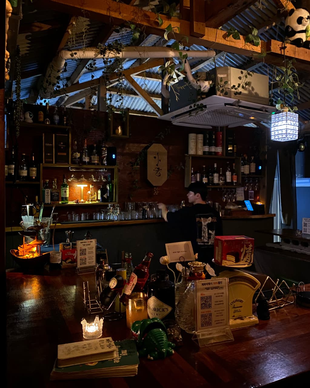 제주특별자치도 제주시 제주아홉 혼술바 본점 협재점 바(Bar) - 조명 아래 나무 다찌석과 위스키 병이 배치된 공간에서 1인 혼술을 즐기는 상황