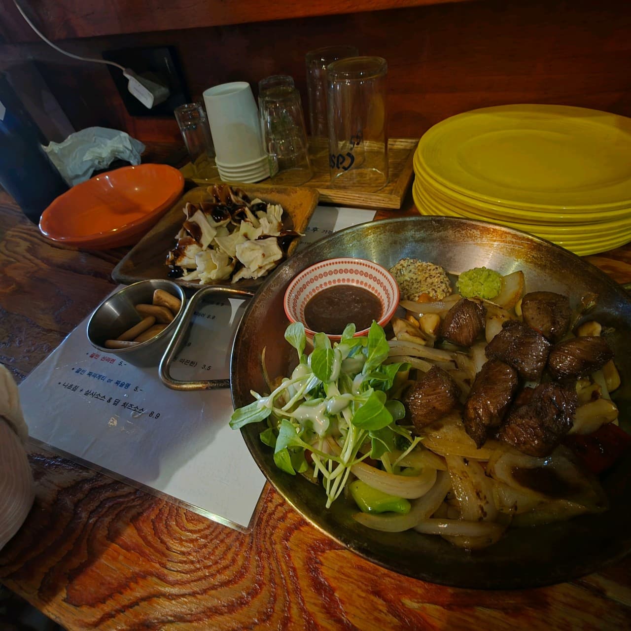 대전광역시 중구 심야식당11월6일 대전의 다찌석 1인 혼술. 노란 조명 아래 육즙 있는 큐브 스테이크와 구운 채소, 기타 안주가 차려진 정갈한 술상 상황.