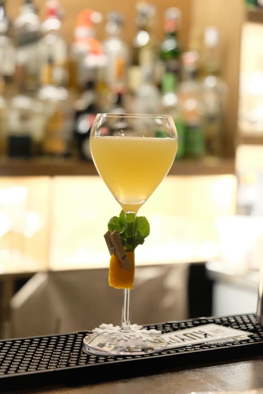 대전광역시 동구 공강 대전 바(Bar) 다찌석 위 노란색 칵테일과 허브 가니쉬. 오렌지 껍질이 고정된 술잔과 조명 아래 진열된 술병들이 어우러진 혼술 상황.