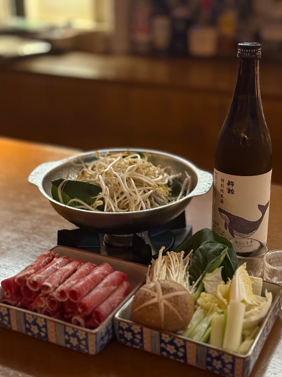 대전광역시 서구 혼술 이자카야 월정 대전 - 다찌석 조명 아래 선홍빛 소고기와 숙주가 담긴 나베, 사케가 차려진 1인 차림