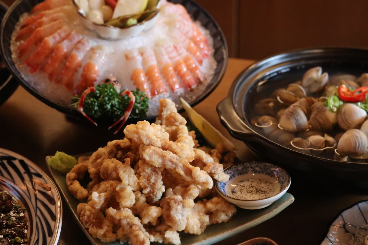 대전광역시 서구 이자카야 월정 대전. 조명 아래 다찌석에 차려진 바삭한 튀김, 단새우회, 조개탕. 혼술을 위해 테이블 위 배치된 질감이 돋보이는 안주들
