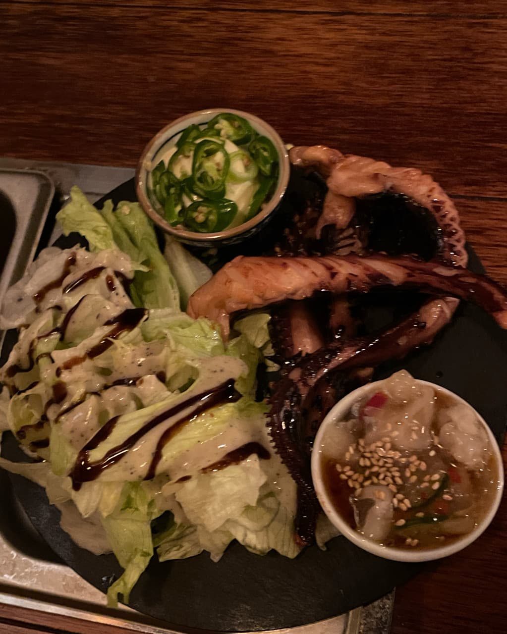 대전광역시 서구 철길부산집 대전관저점 요리주점 다찌석 조명 아래 놓인 문어 구이와 샐러드 소스 구성. 1인 혼술 상황에 어울리는 안주의 시각적 질감.