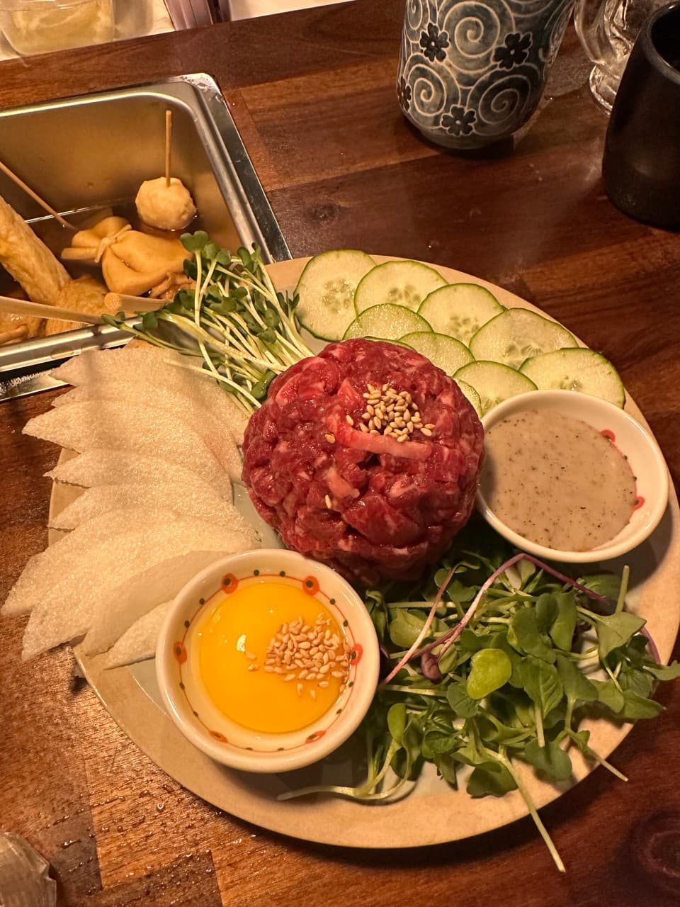 대전광역시 서구 요리주점 철길부산집 대전관저점 다찌석 1인 혼술. 주황빛 조명 아래 선홍빛 육회와 계란 노른자, 어묵탕이 차려진 목재 테이블 상차림.