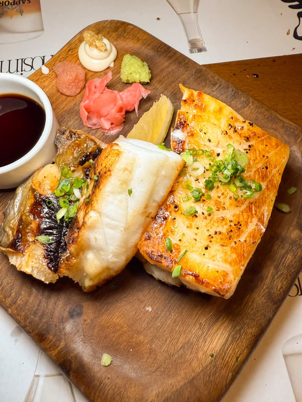 경기도 성남시 이자카야 잔잔 정자역점 경기 1인 다찌석에 차려진 노릇한 생선구이와 고추냉이. 나무 도마 위 소스와 곁들임 음식이 조명 아래 배치된 혼술 상황.