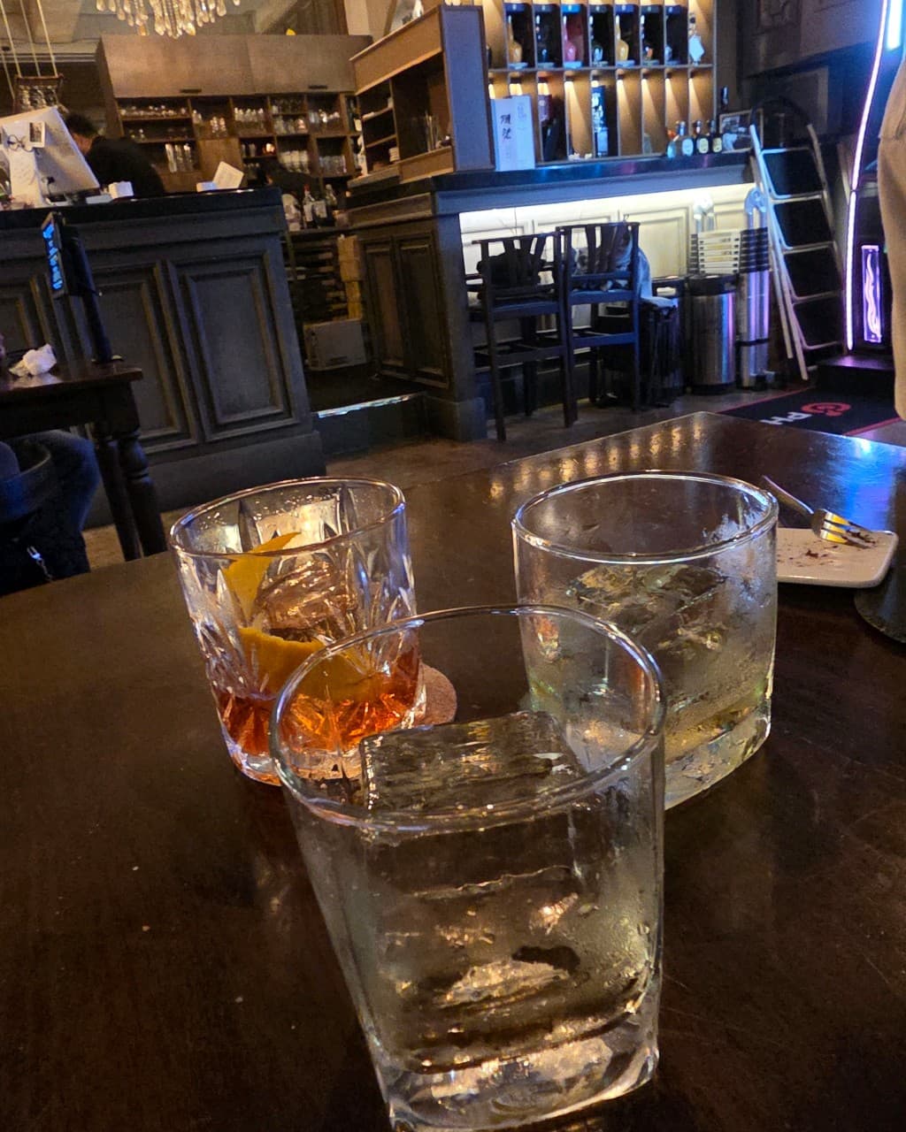 경기도 화성시 드링킹랩 경기 바(Bar) 다찌석 배경. 테이블 위 투명한 각얼음과 오렌지 필이 담긴 칵테일 잔들이 놓인 1인 위스키 혼술 상황.