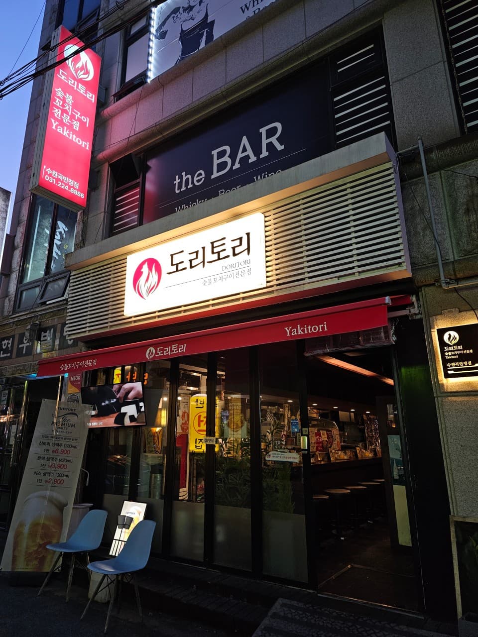 경기도 수원시 혼술 요리주점 도리토리 수원곡반정점 경기 - 환한 간판 아래로 1인 다찌석이 배치된 내부가 보이며 혼술을 즐길 수 있는 저녁 시간 매장 입구 전경