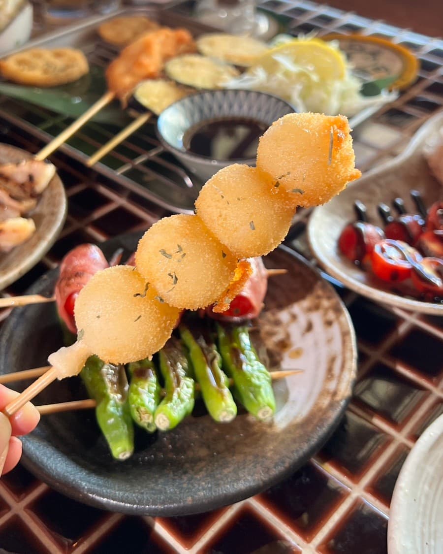 경기도 안산시 숯토리 안산고잔점 경기 이자카야 다찌석 혼술 차림. 타일 테이블 위 바삭한 튀김 꼬치와 구운 꽈리고추가 놓인 1인용 식단과 조명 아래의 질감.