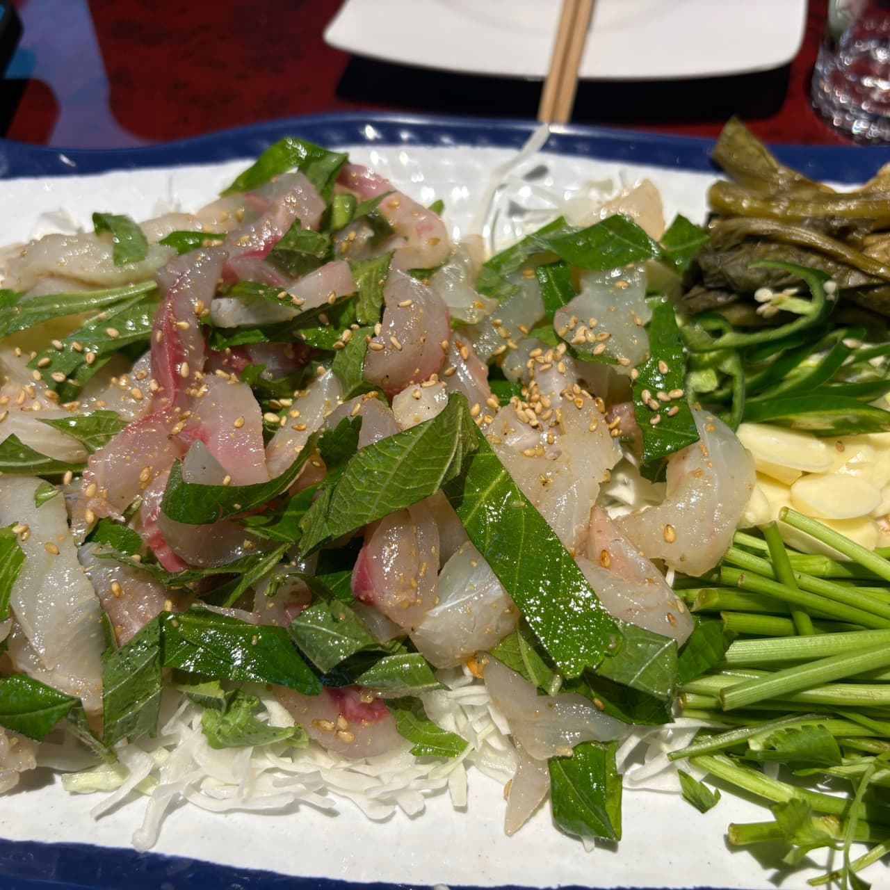 대구광역시 달서구 영남막회초장 상인본점 대구 다찌석에서 즐기는 혼술. 조명 아래 양배추와 깻잎이 섞인 막회의 질감과 마늘, 고추가 차려진 1인 식사 상황.