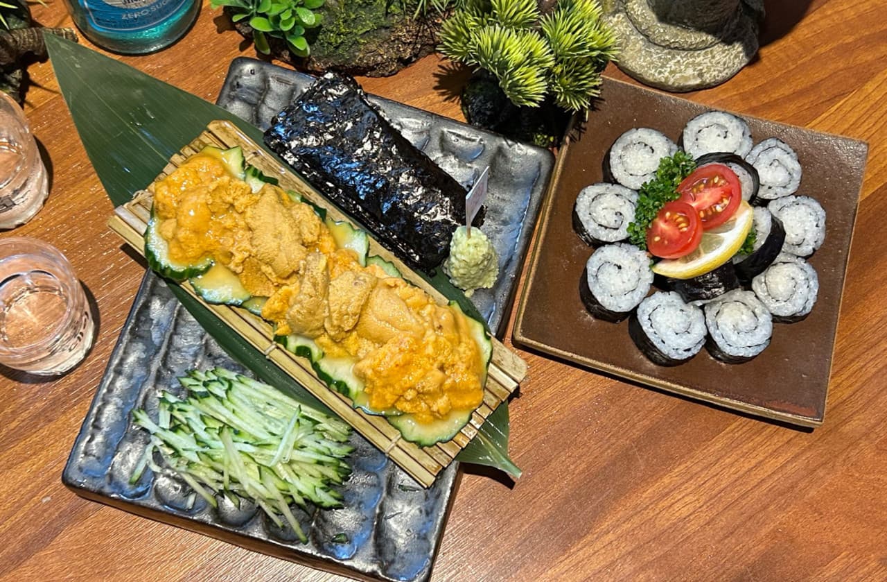 인천광역시 계양구 일월육일 인천계양점 이자카야 다찌석. 나무 테이블 위 성게알, 김, 오이채, 마끼가 차려진 혼술 상차림과 조명이 비치는 1인 안주의 질감.
