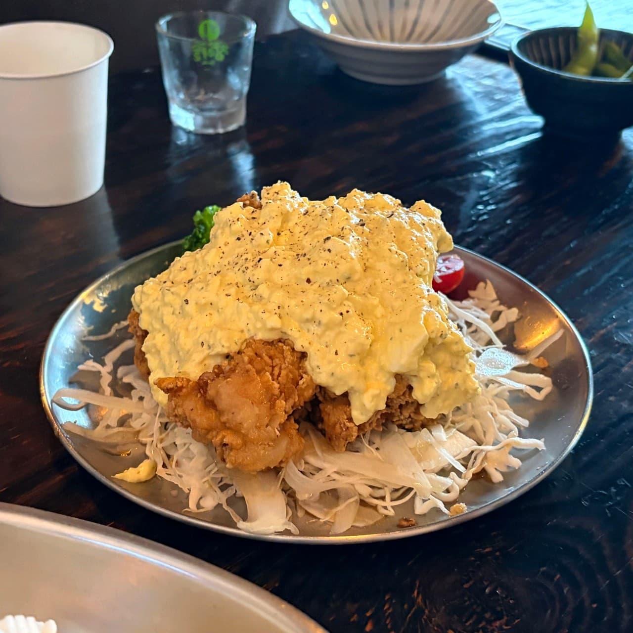인천광역시 서해구 이고식당 인천 이자카야 다찌석 혼술 상황. 조명 아래 타르타르 소스를 듬뿍 얹은 가라아게와 양배추 채가 담긴 스테인리스 접시가 놓인 모습.