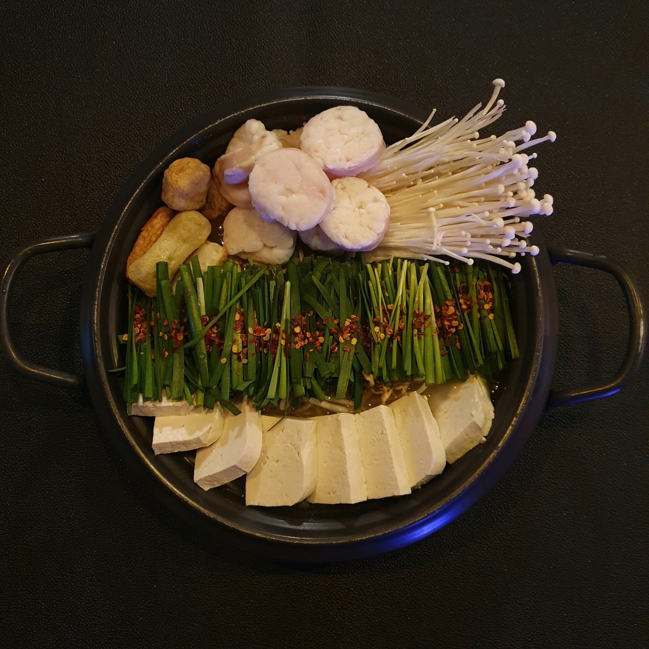 인천광역시 영종구 요리주점 촤랑 인천 다찌석 조명 아래 배치된 모츠나베. 대창, 부추, 팽이버섯, 두부가 담긴 전골 냄비로 구성된 1인 혼술 상차림.