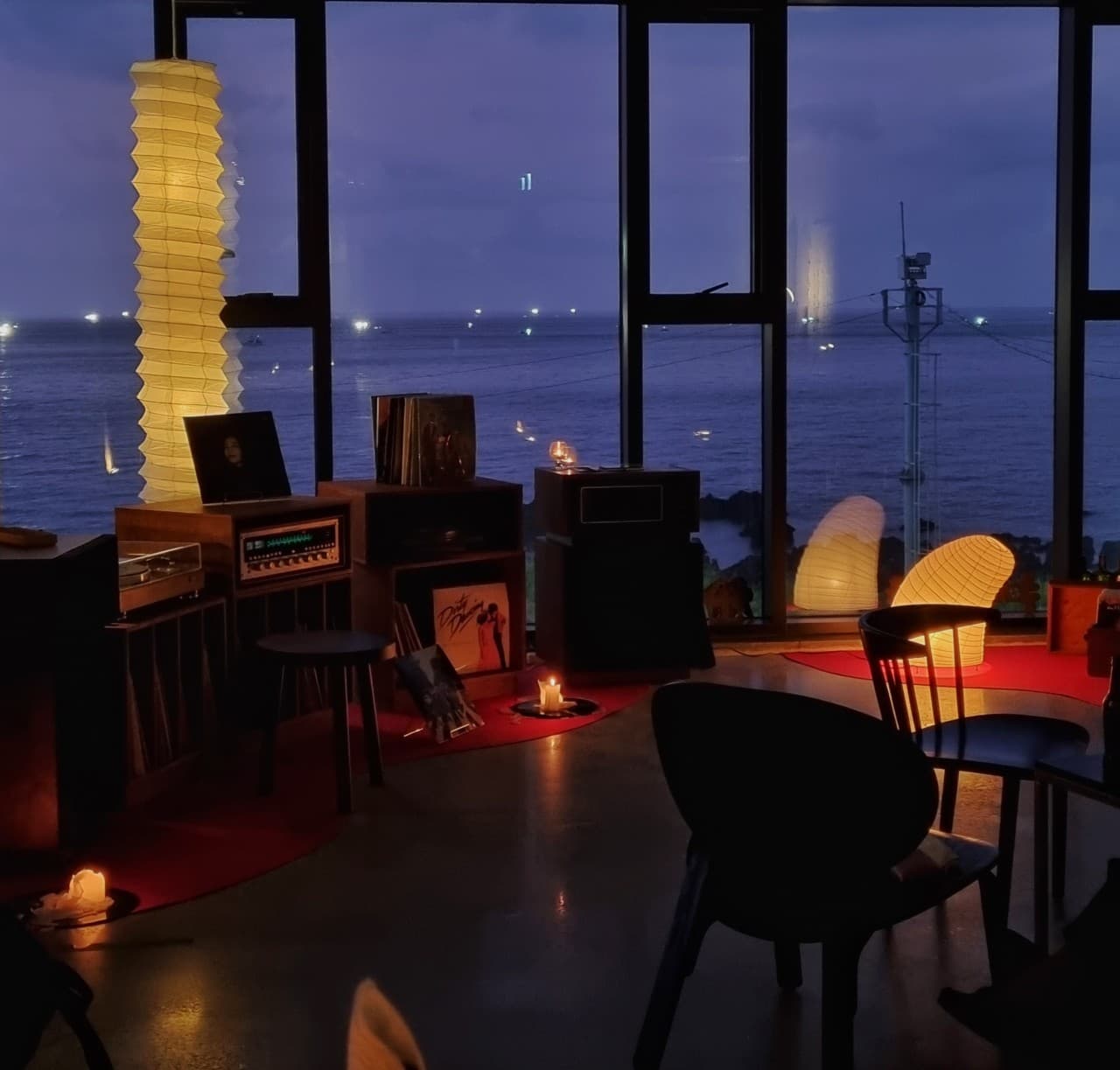 제주특별자치도 제주시 내도음악상가 제주 와인바. 바다 전망 창가 앞 LP 플레이어와 노란 종이 조명, 촛불 옆 1인용 좌석에서 즐기는 혼술 상황.