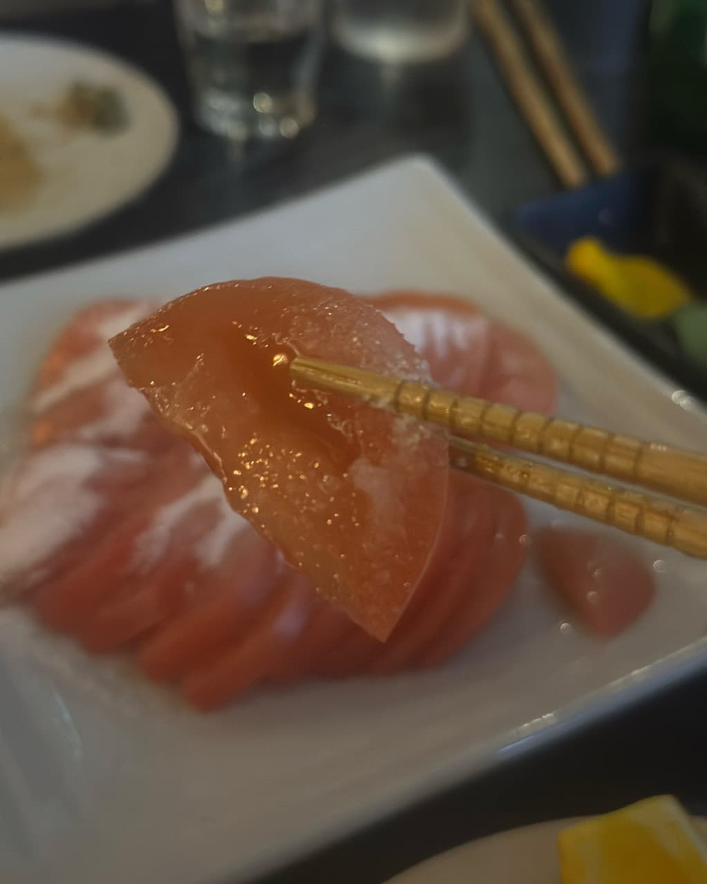 울산광역시 북구 오사카로맨스 매곡점 이자카야 다찌석 혼술 중 젓가락으로 집어 올린 윤기 나는 사시미와 어두운 조명 아래 테이블.