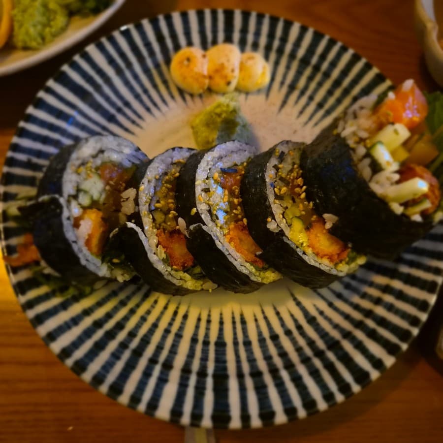 울산광역시 남구 찰랑 울산달동본점 요리주점 조명 아래 1인 다찌석에 차려진 후토마키. 줄무늬 접시 위 바삭한 튀김과 연어가 채워진 속재료와 와사비가 곁들여진 혼술 상황.