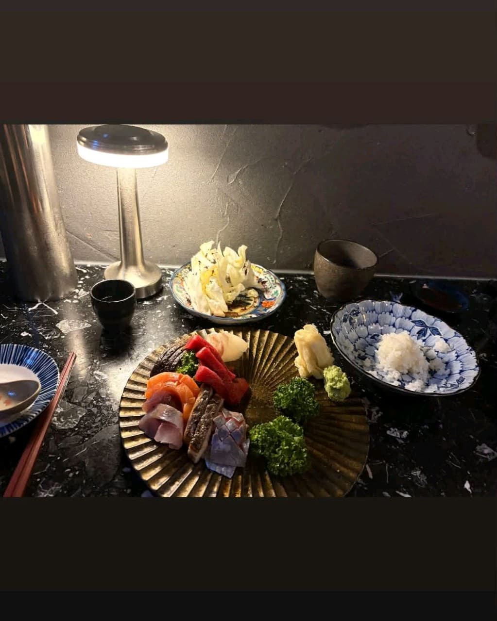 강원특별자치도 속초시 속초레몽 이자카야 다찌석 조명 아래 놓인 1인 사시미와 밥. 검은 대리석 테이블 위 연어와 참치 등 모듬 회가 차려진 혼술 상황.