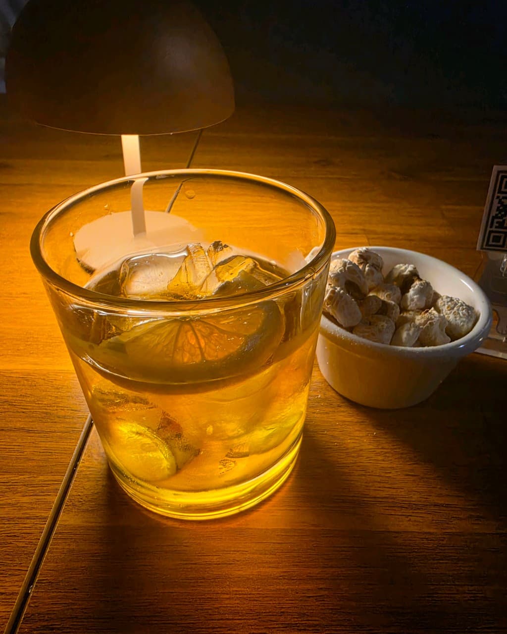 강원특별자치도 강릉시 주인 강릉혼술바 강릉점 바(Bar) 조명 아래 1인 다찌석에 차려진 레몬 하이볼과 하얀 그릇에 담긴 옥수수 과자가 있는 혼술 상황