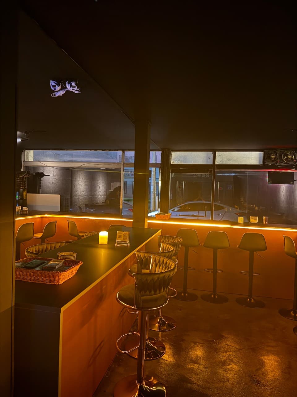 강원특별자치도 강릉시 낭만혼술바 강릉역점 바(Bar). 주황색 조명 아래 캔들이 놓인 긴 다찌석과 1인용 의자가 정렬된 혼술 공간