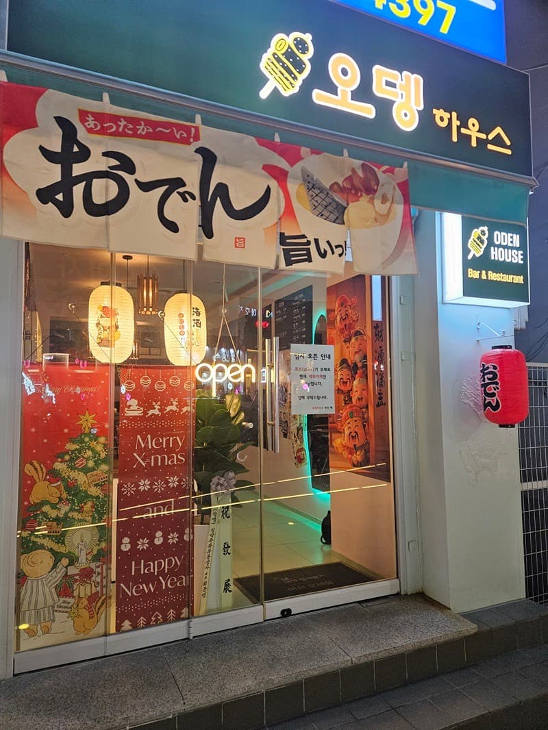 강원특별자치도 속초시 오뎅하우스 오뎅바 - 초록색 간판과 노렌이 걸린 입구. 제등 조명 아래 혼술용 다찌석이 보이는 통유리창과 크리스마스 포스터가 붙은 모습.