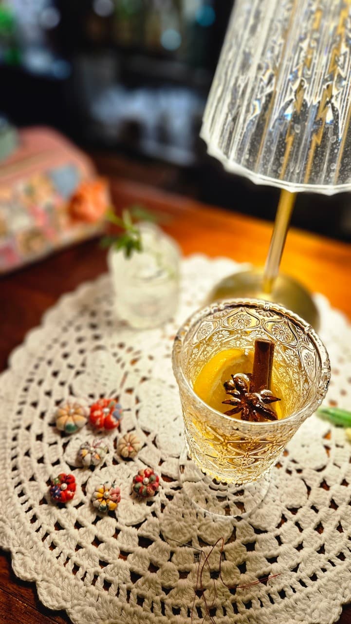 강원특별자치도 철원군 쁘띠클로젯 사사로운공간 바(Bar)의 조명 아래 1인 혼술. 레이스 매트 위 레몬과 시나몬이 담긴 크리스탈 잔과 수공예 소품이 놓인 다찌석 풍경