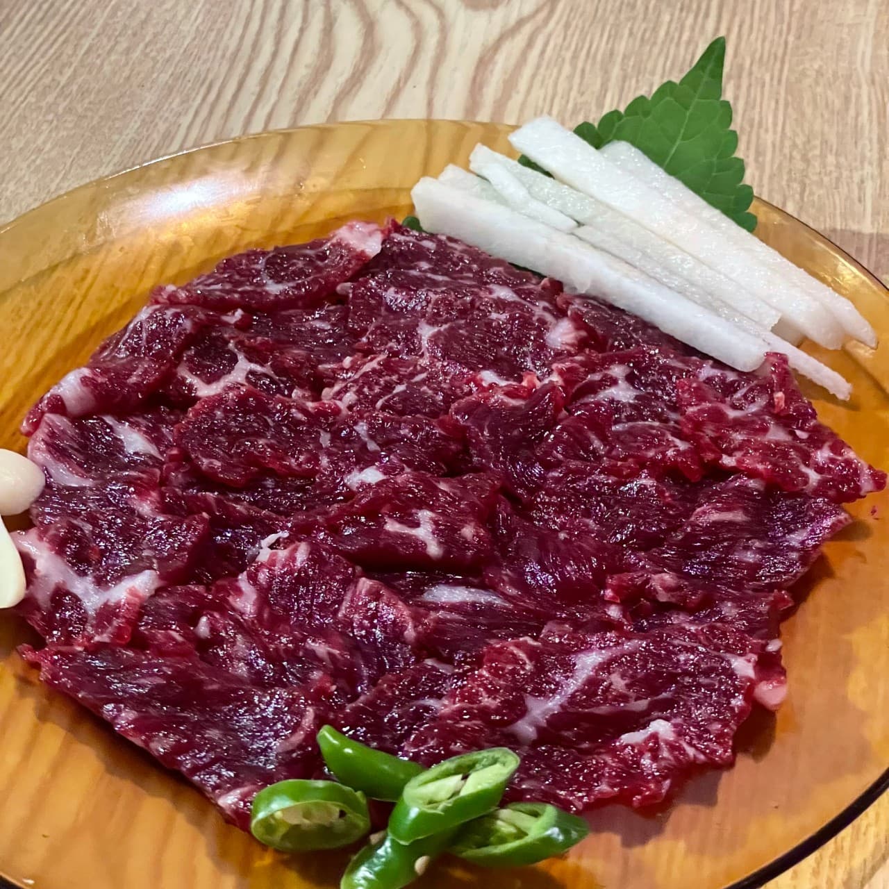 강원특별자치도 속초시 요리주점 아프리카 1인 다찌석에 차려진 선홍빛 육사시미와 채 썬 배. 나무 테이블 조명 아래 고기 질감이 돋보이는 안주와 혼술 상황.