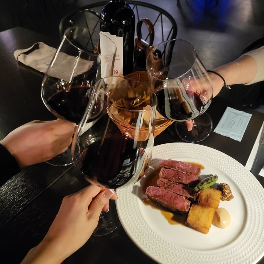 세종특별자치시 시청대로 라운지 알트 와인바 다찌석에서 즐기는 1인 스테이크와 레드 와인. 조명 아래 와인잔을 부딪히는 상황과 육질이 선명한 고기 단면이 차려진 테이블 구성.