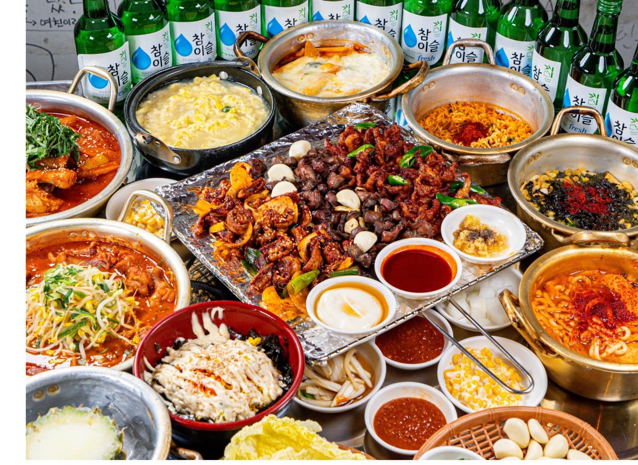 세종특별자치시 나성로 요리주점 계화동 세종점 1인 다찌석. 매콤한 닭발과 똥집 구이, 라면, 주먹밥이 차려진 혼술 상차림과 여러 병의 소주.