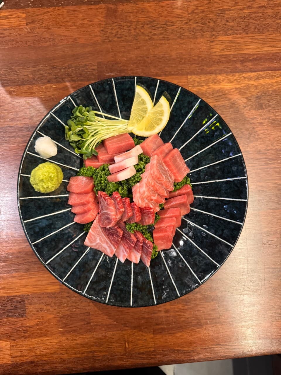 경상남도 김해시 튜나펍 김해주촌점 조명 아래 원목 다찌석 1인 참치 사시미. 푸른색 접시에 담긴 붉은 참치회와 와사비가 차려진 주점 혼술 상황