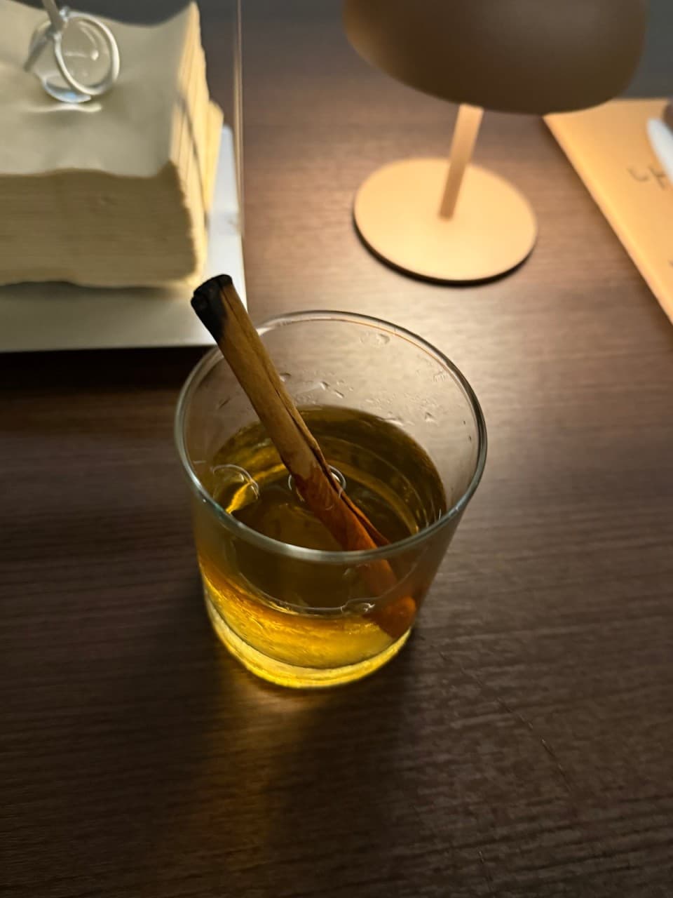경상남도 창원시 꼼바혼술바 창원상남점 바(Bar)의 다찌석. 시나몬 스틱을 넣은 칵테일과 테이블 조명 빛이 닿는 우드 테이블 위에서 혼자 잔을 기울이는 혼술 상황.
