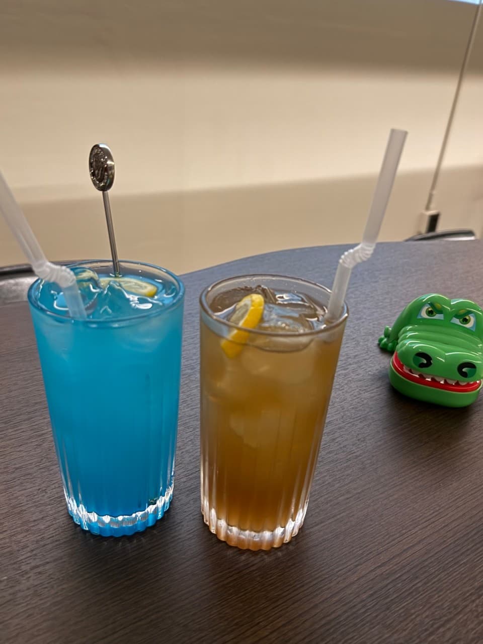 경상남도 창원시 꼼바혼술바 창원상남점 바 테이블 위 레몬을 곁들인 파란색 칵테일과 하이볼. 악어 장난감이 놓인 1인석에서 즐기는 혼술 상황.