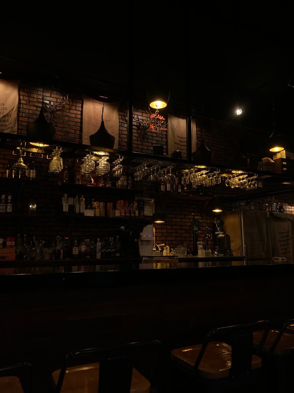 충청북도 음성군 512saloon 펍&바 내부 바 카운터석. 붉은 벽돌과 노란 핀 조명 아래 정렬된 술잔과 혼술을 위한 다찌석이 배치된 바(Bar) 전경.