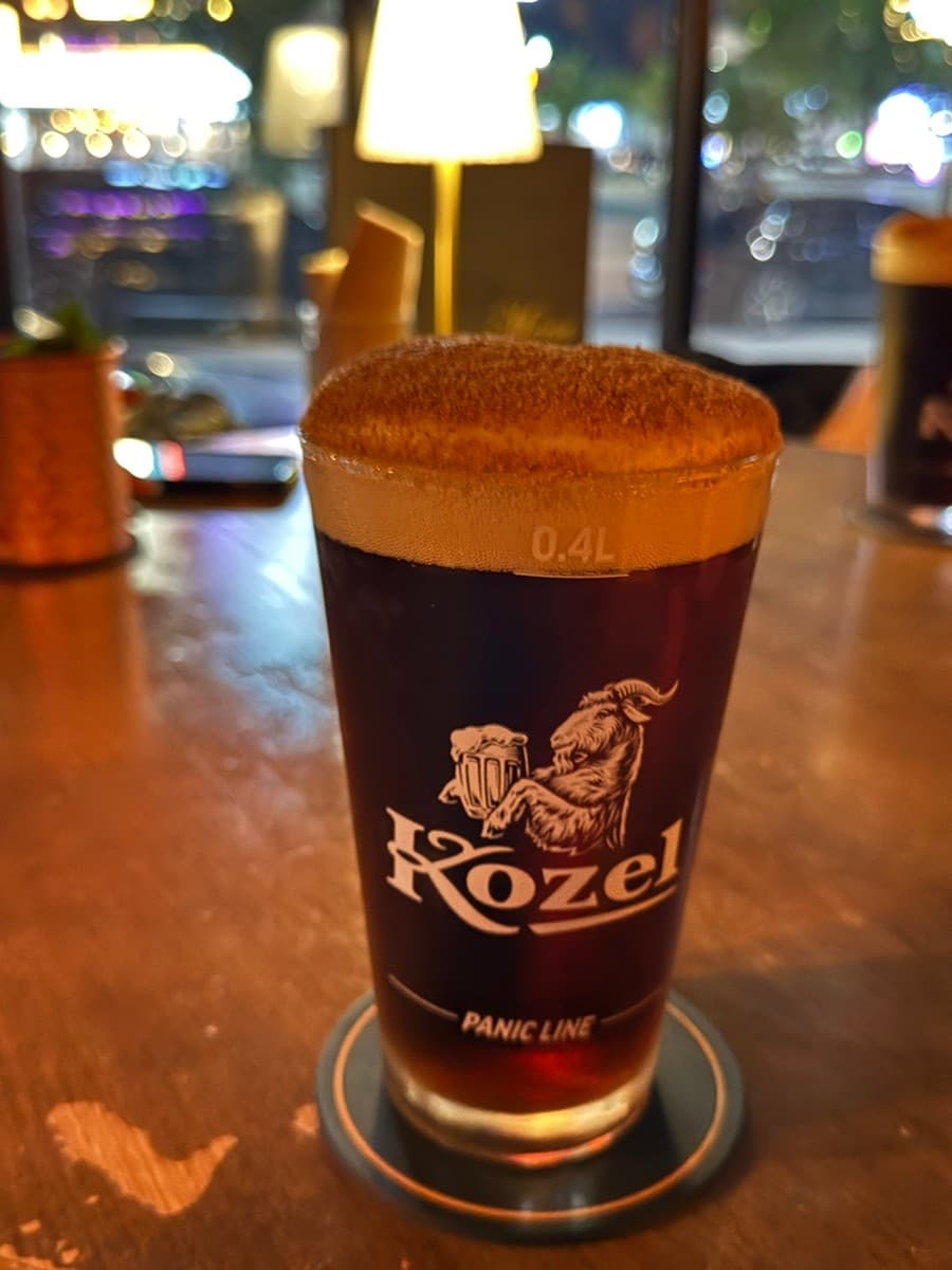 충청북도 음성군 512saloon 펍&바 바(Bar) 1인 혼술. 시나몬 가루를 얹은 코젤 다크 맥주가 조명 아래 나무 다찌석에 놓인 상태.