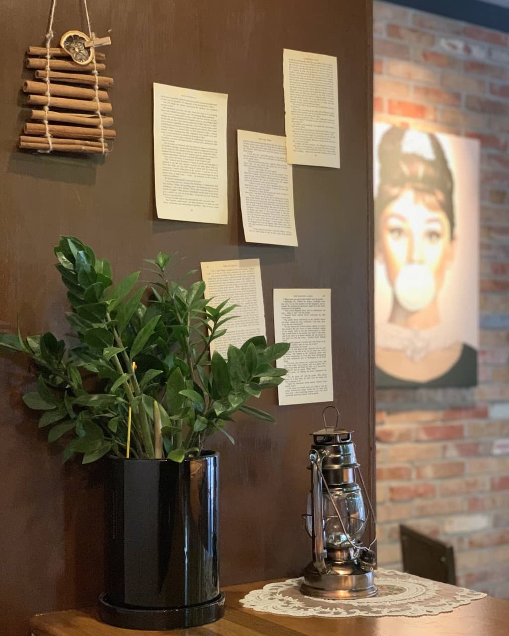 충청북도 청주시 기니쉬커피바 바(Bar) 내부. 황색 조명 아래 초록색 화분과 빈티지 등불이 놓인 혼술 공간. 나무 벽면의 페이퍼와 벽돌 배경의 인물 포스터.