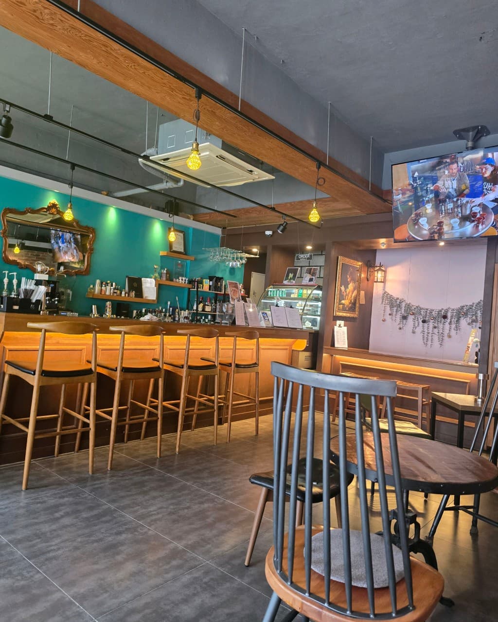 충청북도 청주시 기니쉬커피바 바(Bar) 실내. 노란 펜던트 조명이 비추는 나무 다찌석과 높은 의자가 있는 1인 혼술 공간 및 민트색 벽면.