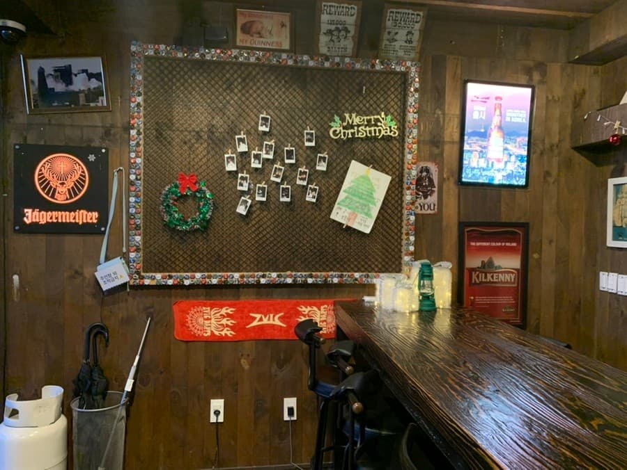 충청북도 제천시 보틀넥 바(Bar) - 나무 질감의 1인 다찌석과 낮은 조명 아래 예거마이스터 간판이 설치된 혼술 공간