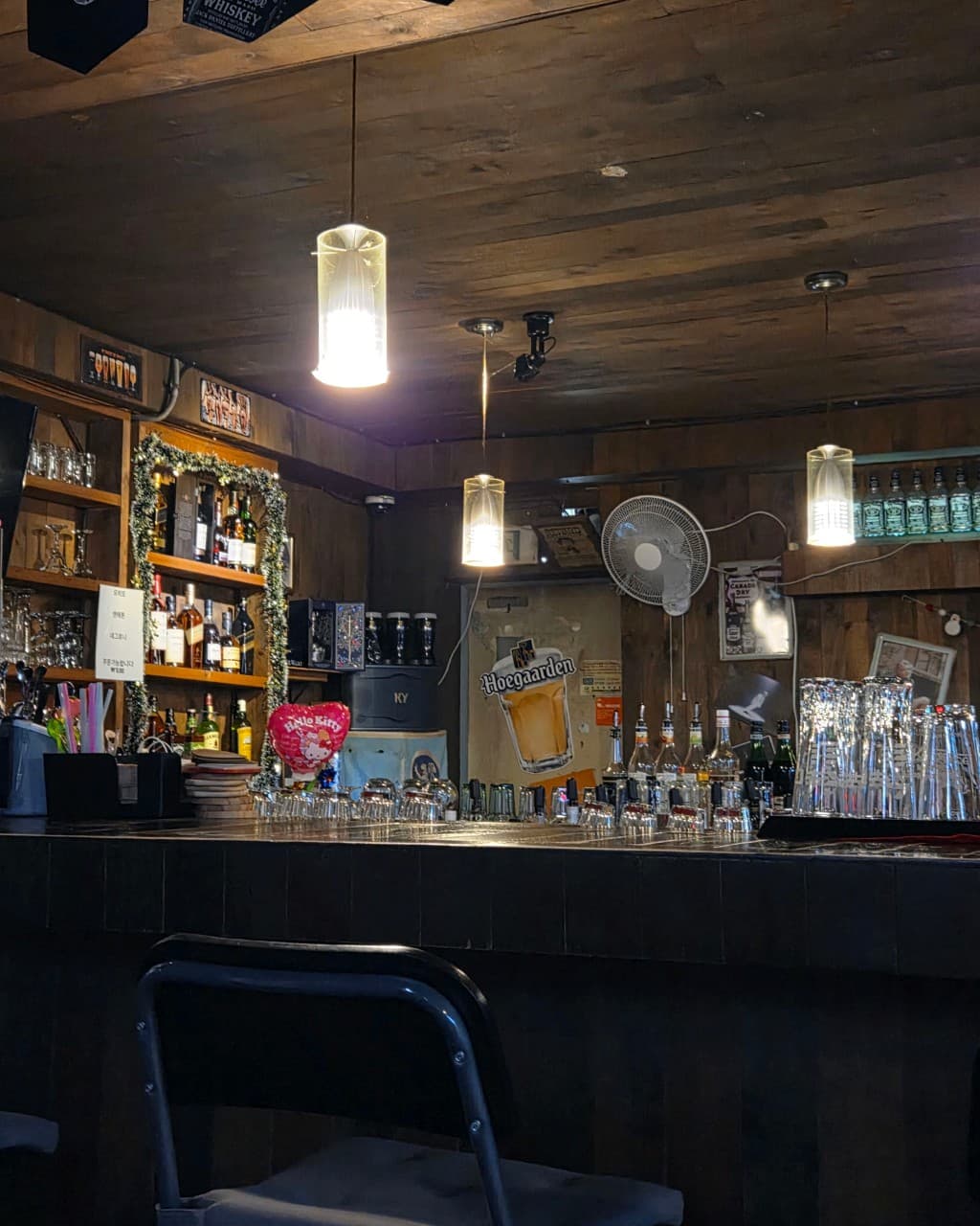 충청북도 제천시 보틀넥 바(Bar) - 펜던트 조명이 내려앉은 목재 다찌석과 벽면 선반에 진열된 다양한 위스키 병들이 어우러진 1인 혼술 공간