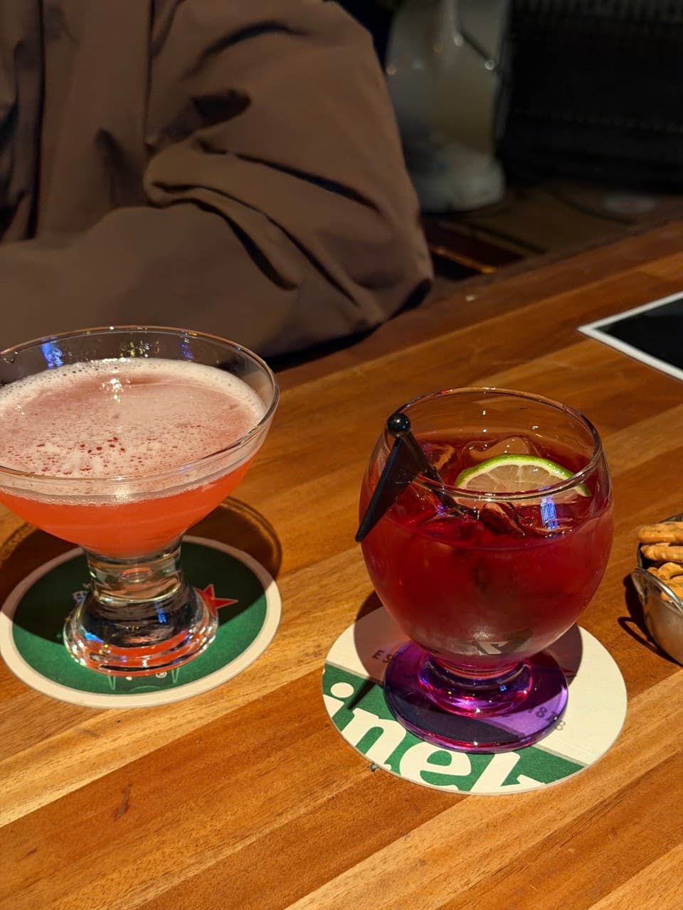 충청북도 청주시 혼술 바(Bar) 라온 - 어두운 조명 아래 나무 다찌석과 붉은 빛 칵테일. 라임 조각과 거품의 질감이 보이는 1인석 테이블 상황