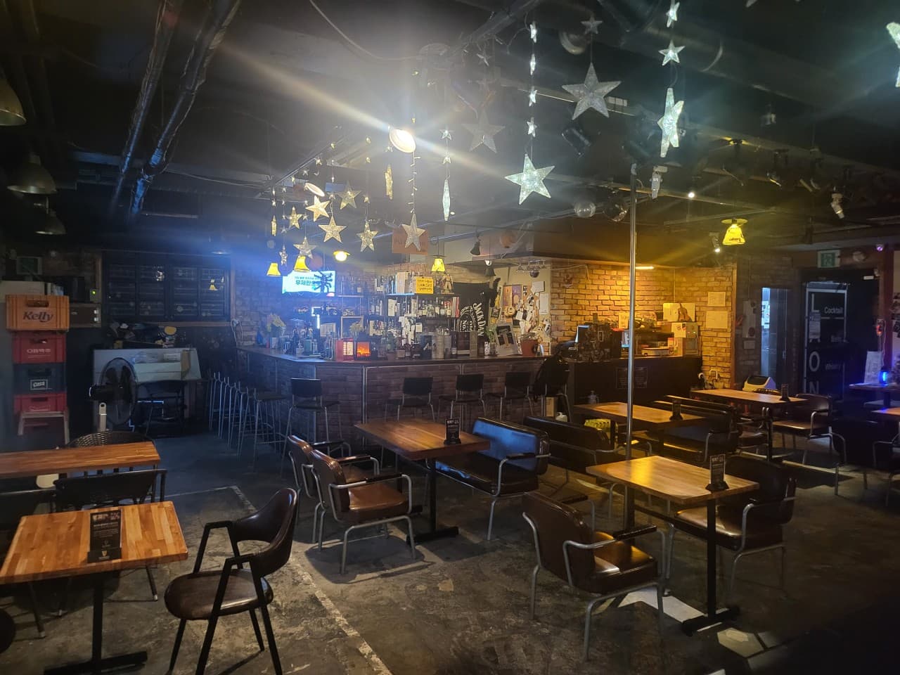 충청북도 청주시 라온 바(Bar) - 별 모양 조명 아래 목재 테이블과 1인 다찌석. 벽돌 벽면과 술병이 진열된 카운터에서 혼술을 즐기는 환경을 구성함.