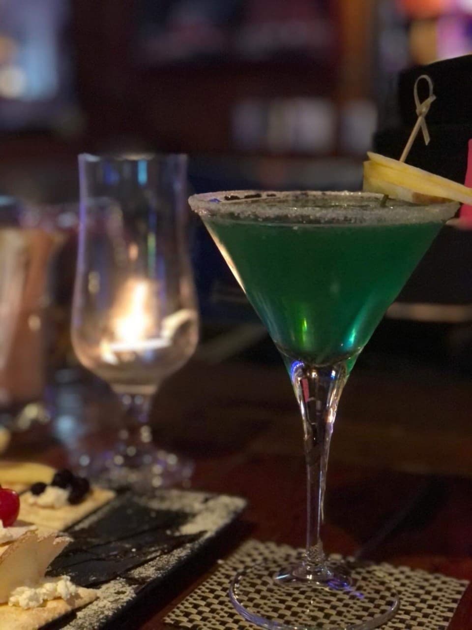 충청북도 제천시 웨스턴빌리지 바(Bar) 혼술 현장. 설탕 리밍된 초록색 칵테일과 과일 가니쉬, 촛불 조명이 비치는 다찌석 테이블에 차려진 크래커 안주.