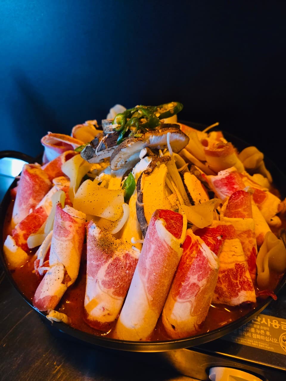 충청북도 충주시 맥주,호프 빈잔의 집중 조명 아래 다찌석 1인 소고기 전골과 버섯. 선홍빛 육질이 드러나는 어두운 공간에서의 혼술 상황.
