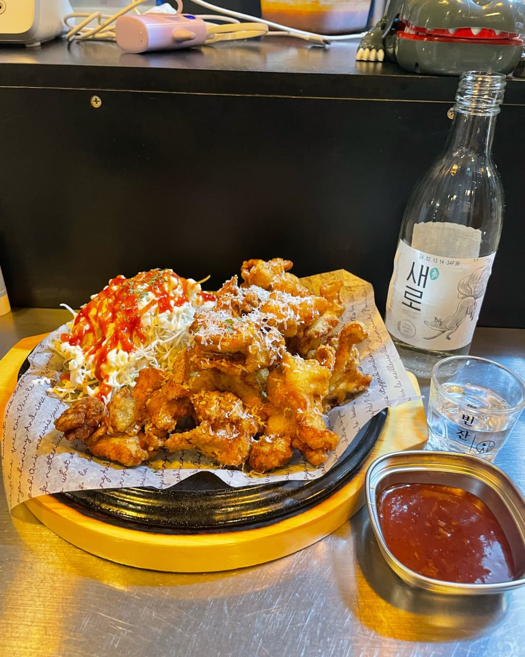 충청북도 충주시 맥주 호프 빈잔의 1인 다찌석 테이블. 치즈 가루를 뿌린 튀김 안주와 소주 한 병이 조명 아래 놓여 혼술하는 상황을 보여줌.