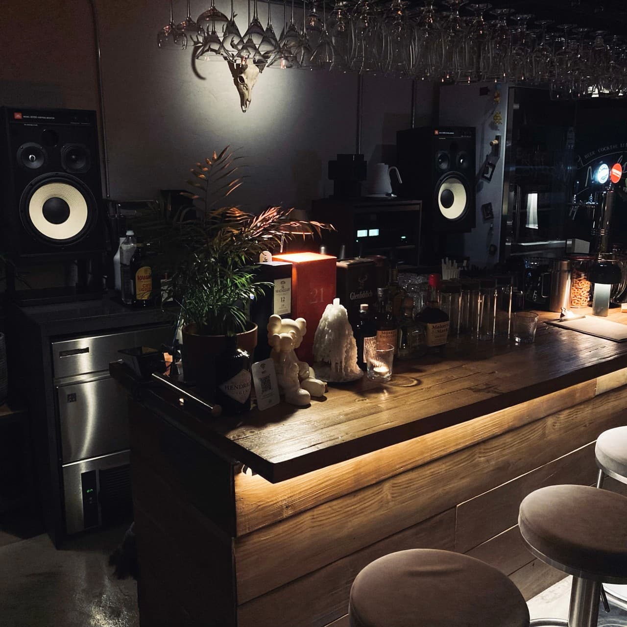 충청북도 충주시 매드슬로우 용산 바(Bar) 하단 조명이 비치는 원목 다찌석과 1인용 의자. 대형 스피커와 위스키 병들이 진열된 테이블에서 혼술을 즐기는 상황.