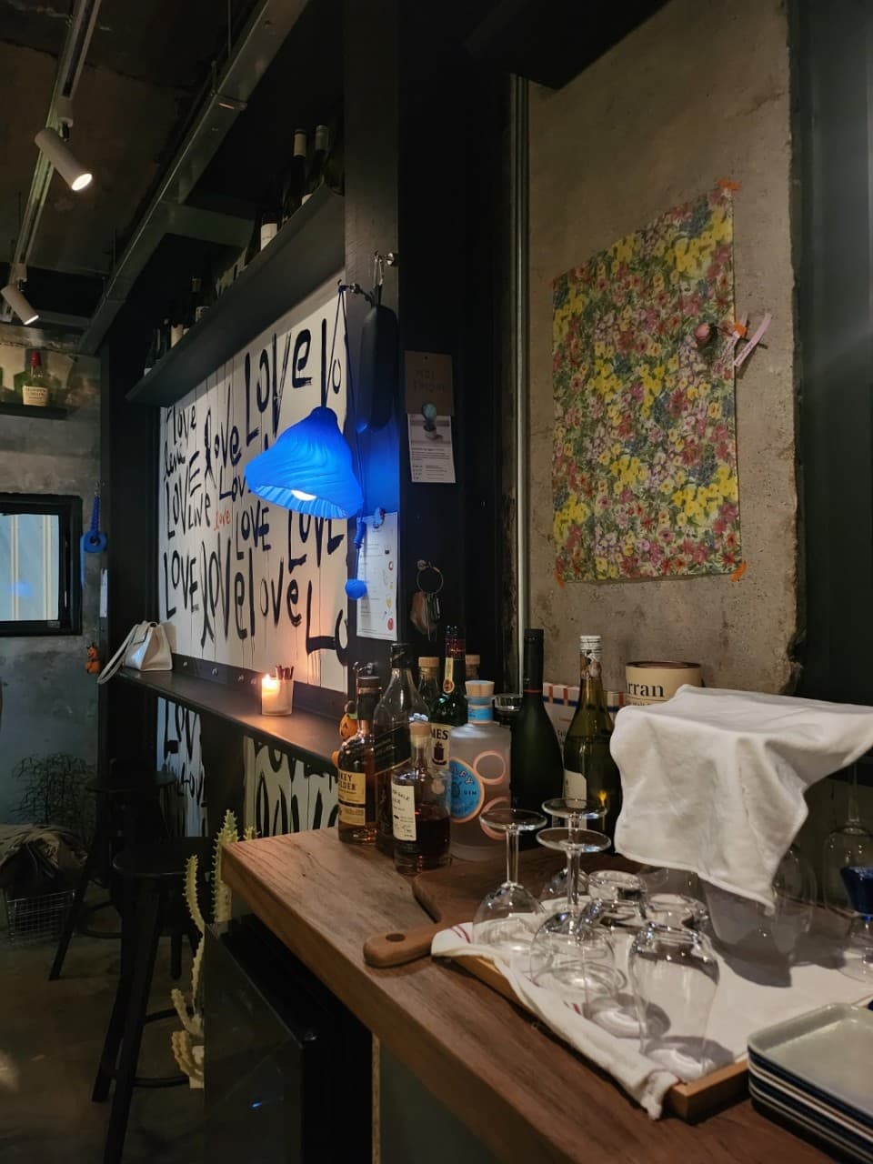 충청북도 충주시 바 뚤리 내부에 위치한 1인 다찌석. 푸른 전등과 캔들 광원 아래 위스키 병과 유리잔이 놓인 혼술 상황.