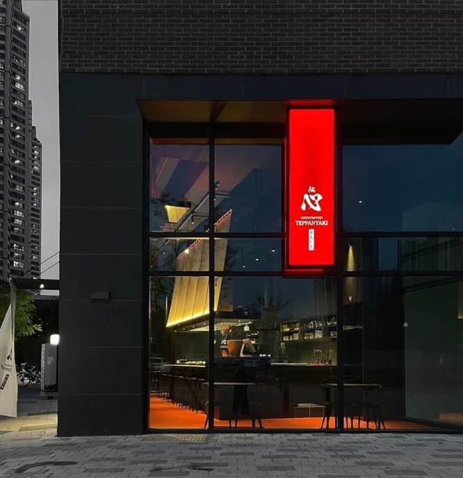 충청북도 청주시 요리주점 전심 - 붉은 간판 아래 통유리창 너머로 보이는 일렬로 배치된 다찌석과 오렌지색 조명 아래 혼술 좌석이 마련된 공간