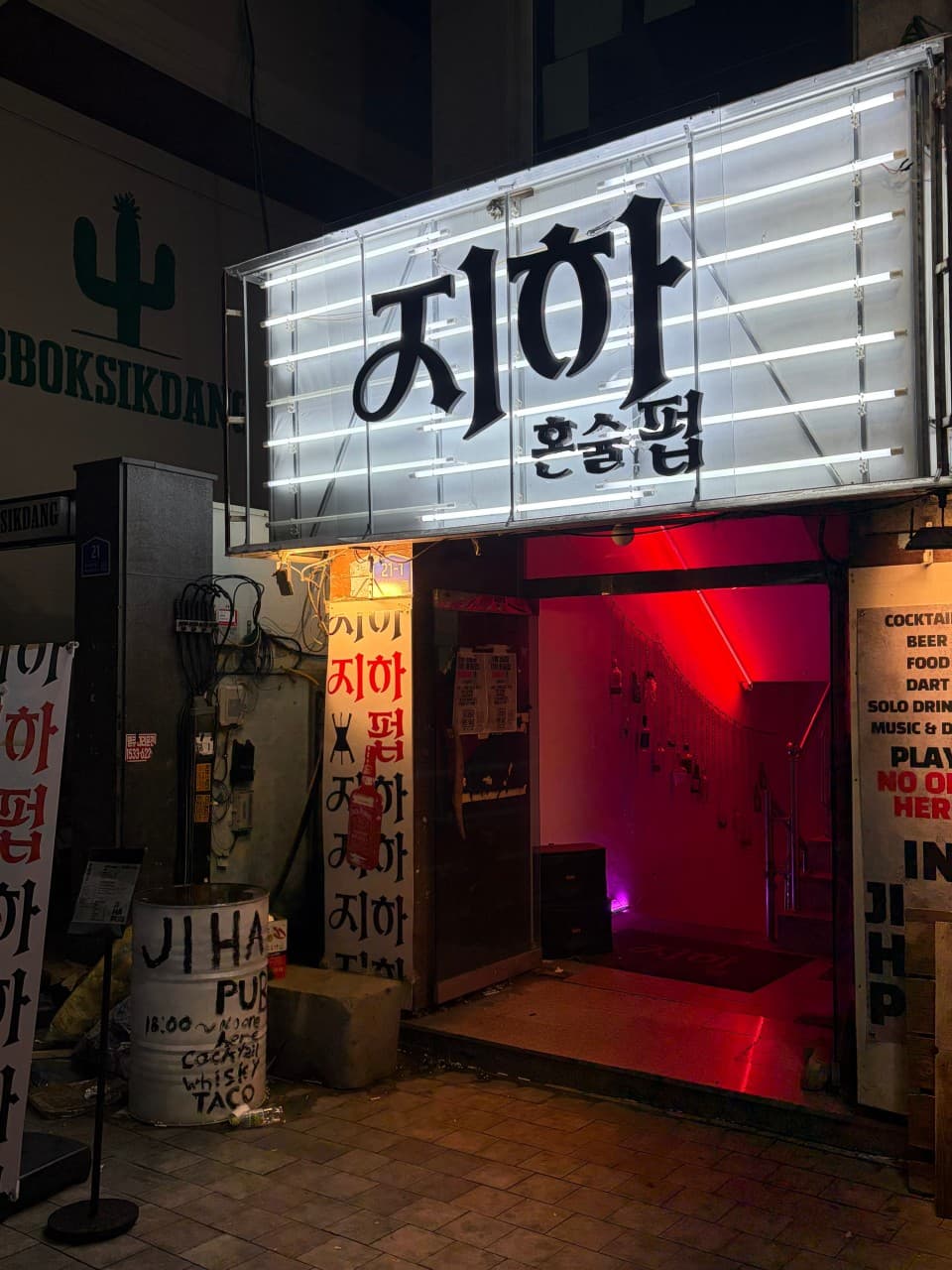 충청남도 천안시 혼술바 지하 혼술펍 - 백색 형광등 간판 아래 붉은 조명이 켜진 지하 계단 입구로 들어가는 1인 중심 바(Bar).