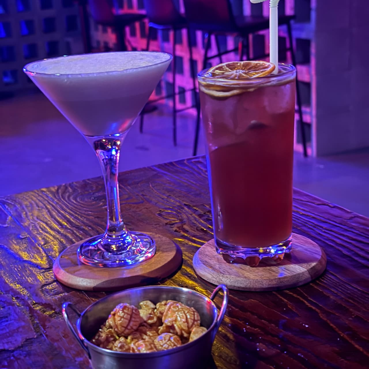 충청남도 천안시 혼술바 지하 혼술펍 바(Bar) 보라색 네온 조명 아래 나무 테이블 위 칵테일과 팝콘이 놓인 1인 다찌석 혼술 상황