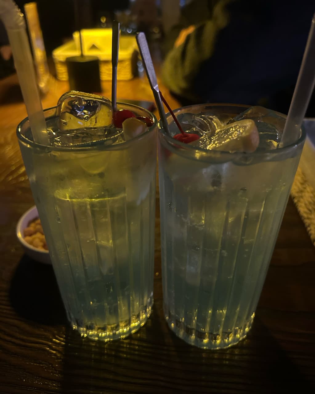 충청남도 천안시 제주아홉 혼술바 천안신불당점 바(Bar) 다찌석에 놓인 푸른 하이볼. 얼음과 레몬, 체리가 담긴 잔과 견과류가 낮은 조명 아래 차려진 1인 혼술 상황.